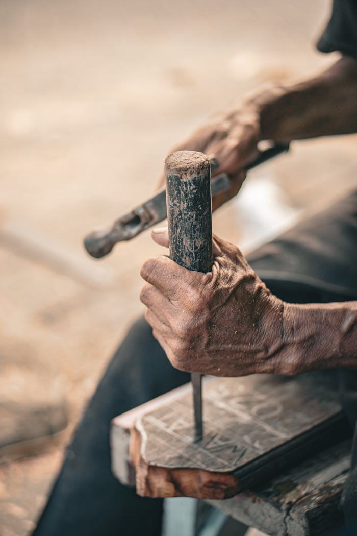hero-img-01 Close-up of an artisan shaping wood with a chisel and hammer.